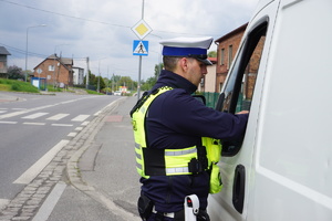 Na zdjęciu policjant nakłada mandat karny na kierowcę, który przekroczył dozwoloną prędkość.