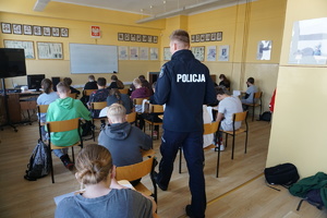 Na zdjęciu policjant oraz uczniowie podczas pisania testu wiedzy o bezpieczeństwie.